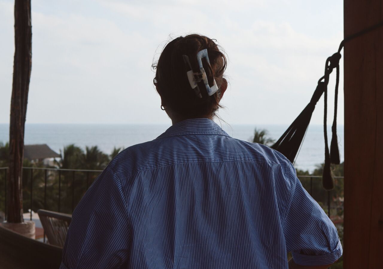 Eine Person steht auf einem Balkon mit Blick auf das Meer.