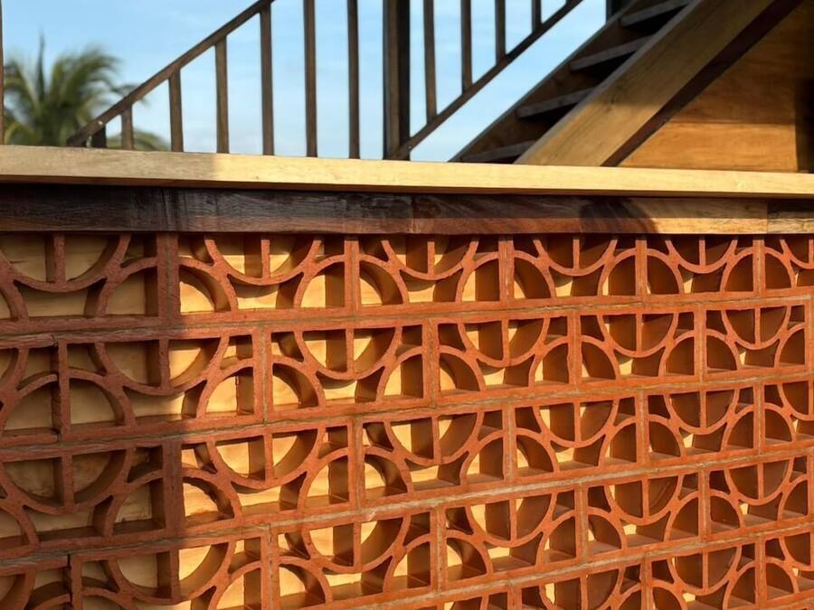 A staircase with a wooden railing and a decorative metal fence with geometric patterns.