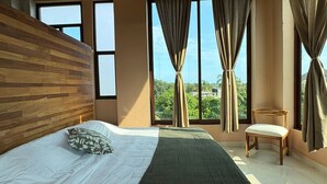 A bedroom with a wooden headboard, a large bed with white and green bedding, a wooden chair, and large windows with curtains. - Casa Ampa Zikatela - Brisas de Zicatela- Puerto Escondido (Brisas de Zicatela)