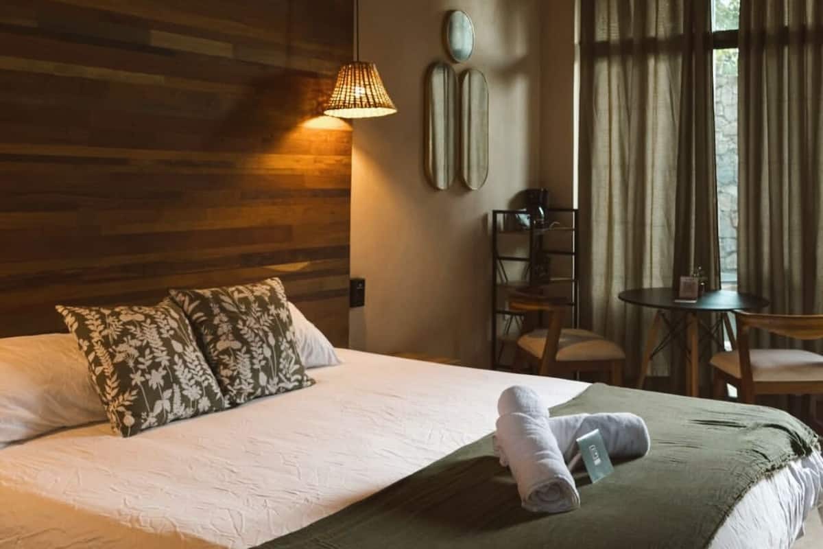 Une chambre d’hôtel avec un lit, une table, des chaises et une lampe.