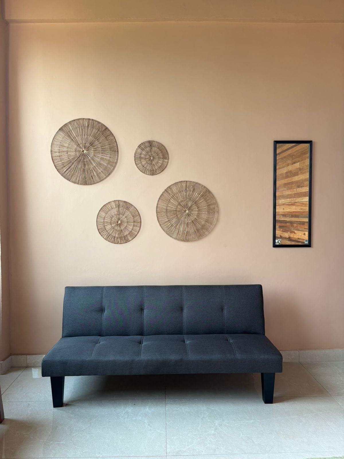A room with a dark blue sofa, four circular wall decorations, and a framed picture on the wall.