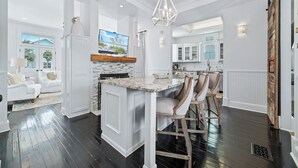A spacious kitchen with a large island, white cabinetry, and a farmhouse sink. - Tannin Luxe 3BR + Loft Bunks, Steps To Beach Access, Pool, Firepit, Water Views (Orange Beach)