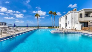 A clear blue pool with a 6 FT depth marker, surrounded by lounge chairs and palm trees, with a building and a fence in the background. - Venice Beach Two Bedroom Private Condo with Community Pool, Gulf Beach Access and Water Views! (Venice)