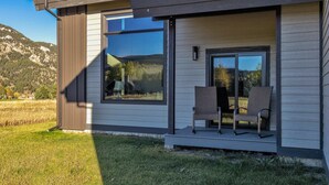 Una casa moderna con un amplio ventanal y un porche con dos sillas.