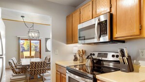 Una cocina moderna con armarios de madera, electrodomésticos de acero inoxidable y un comedor con sillas estampadas.