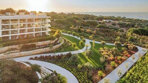 A modern hotel with a rooftop terrace, landscaped gardens, and a view of the sea.