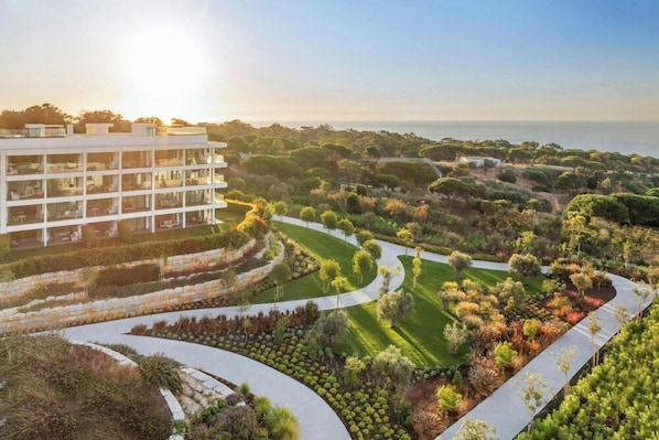 A modern hotel with a rooftop terrace, landscaped gardens, and a view of the sea.
