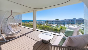 A balcony with a hanging chair, a round table, and a sofa with cushions.
