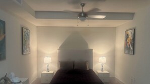 A bedroom with a bed, two bedside tables with lamps, a ceiling fan, and artwork on the walls. - Luxury Loft Penthouse in the Heart of the City with Skyline Views – 1BR, 1.5BA (Austin)