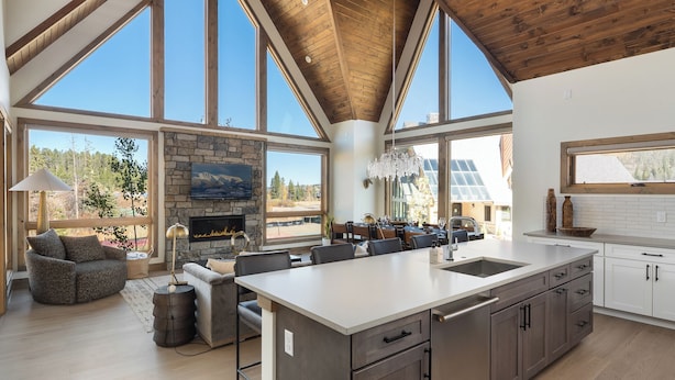 Una cocina amplia con una isla grande, un comedor con chimenea y ventanas grandes que ofrecen vistas al exterior.