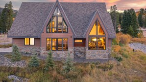 Una casa moderna con fachada de piedra, ventanas amplias y techo inclinado.