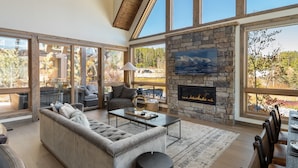 Un salón amplio con chimenea de piedra, ventanas grandes y una zona de estar acogedora.