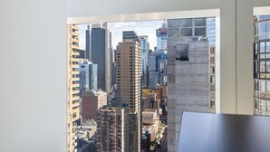 Paesaggio urbano visibile attraverso una finestra, con edifici alti tra cui una struttura in cemento ben evidente.