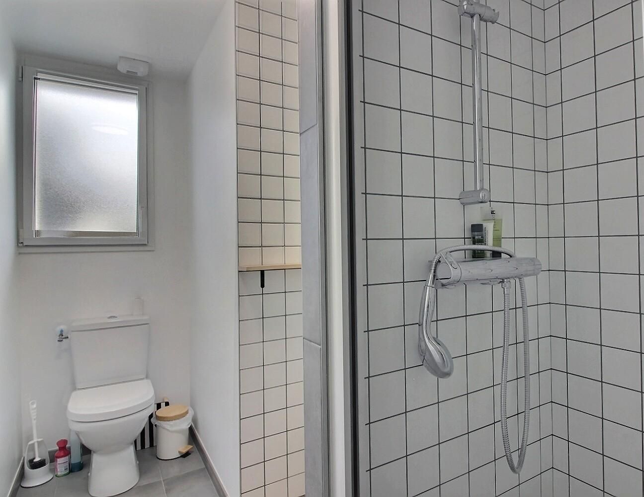 Een moderne badkamer met toilet, bidet en een inloopdouche met handdouche.