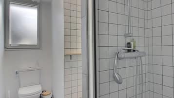 Een moderne badkamer met toilet, bidet en een inloopdouche met handdouche.