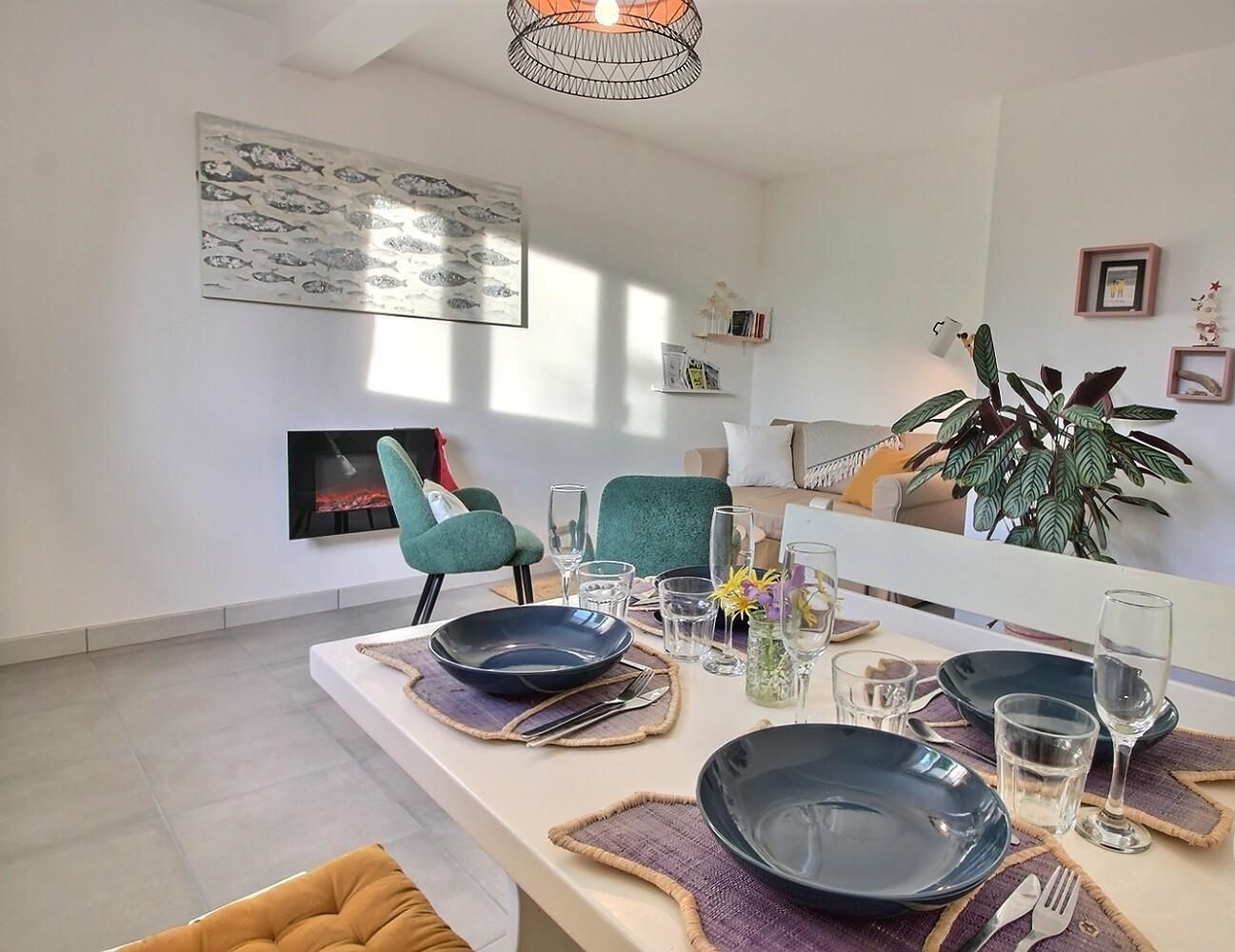 A dining area with a long table set for two, a modern chandelier, and a large fish mural on the wall.
