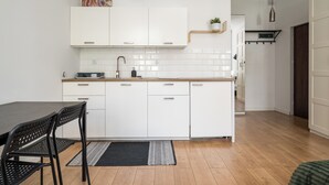 A modern kitchen with white cabinets, a black dining table, and a black rug. - Karolkowa City Comfort Studio (Warszawa)