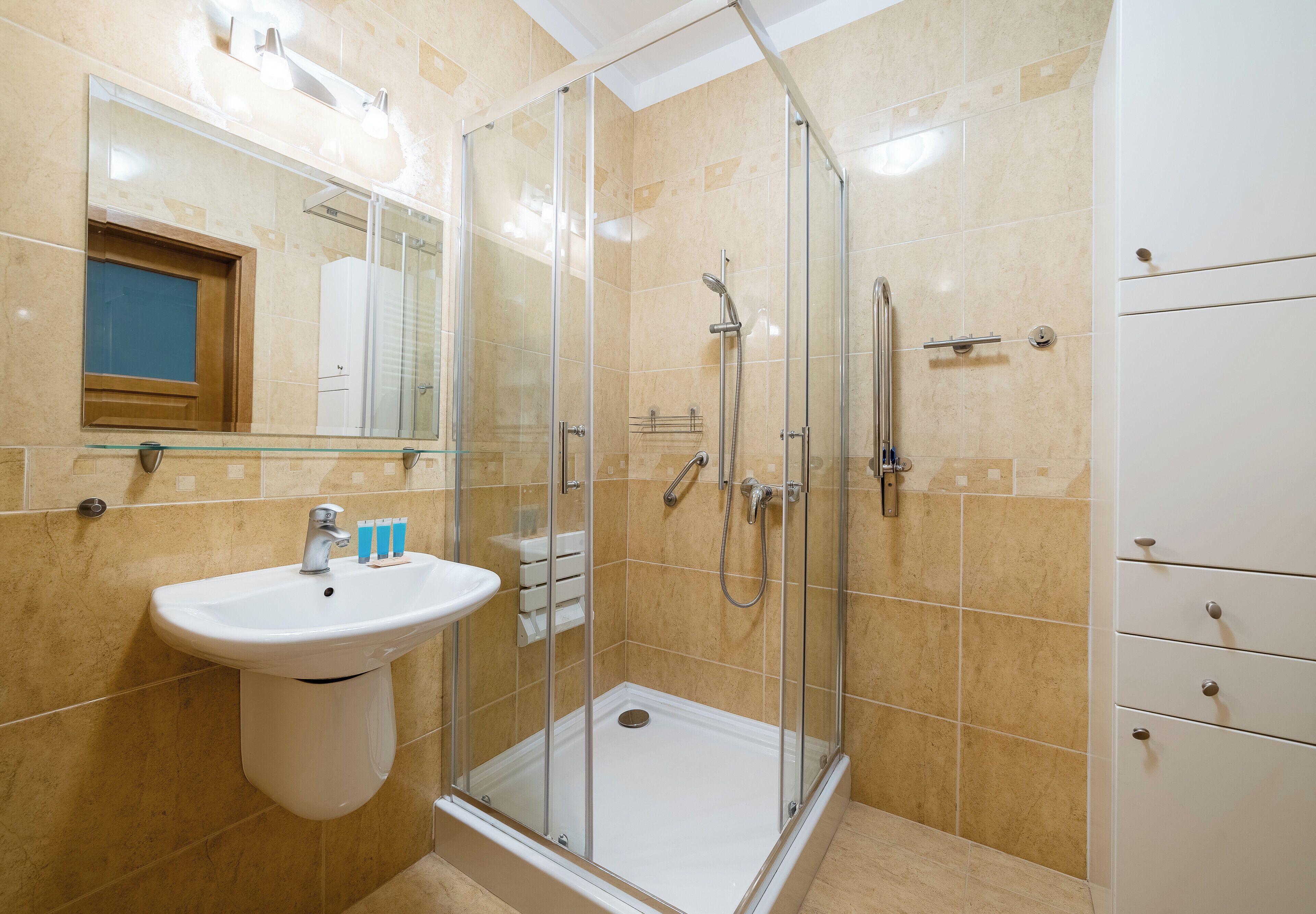 Een badkamer met een douche met glazen wand, een wastafel en een spiegel.
