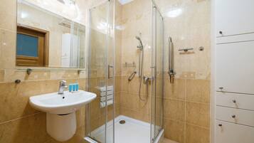 Een badkamer met een douche met glazen wand, een wastafel en een spiegel.
