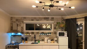 A modern kitchen with a gas stove, oven, microwave, and a hanging light fixture.