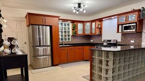 A kitchen with wooden cabinets, a stainless steel refrigerator, a microwave, and a tiled backsplash.