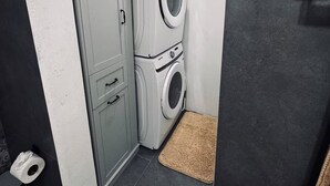A laundry room with a washing machine and dryer, a door, and a small rug on the floor.