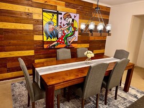 A dining area with a wooden wall, a colorful painting, and a chandelier. - UNMATCHED View from your private rooftop (Noord)