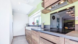 Eine moderne Küche mit Holzausstattung, einer schwarzen Kochplatte und einem Fenster mit Blumen.