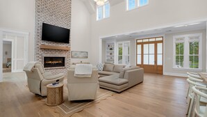 Amplia sala de estar con chimenea de ladrillo, televisor de pantalla plana grande y sofá seccional.