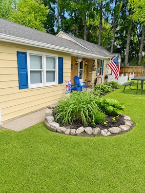 A house with a porch, a flag, and a garden.