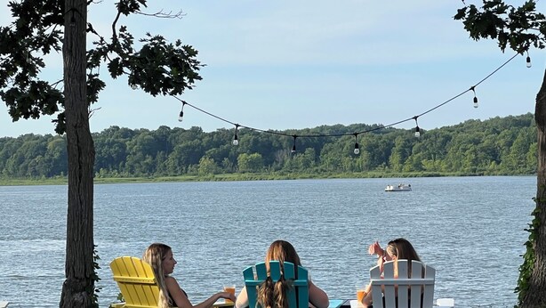 Drei Adirondack-Stühle mit Blick auf einen See, in der Ferne ein Boot.