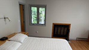 Un dormitorio con cama, mesita de noche, lámpara, ventana y chimenea.