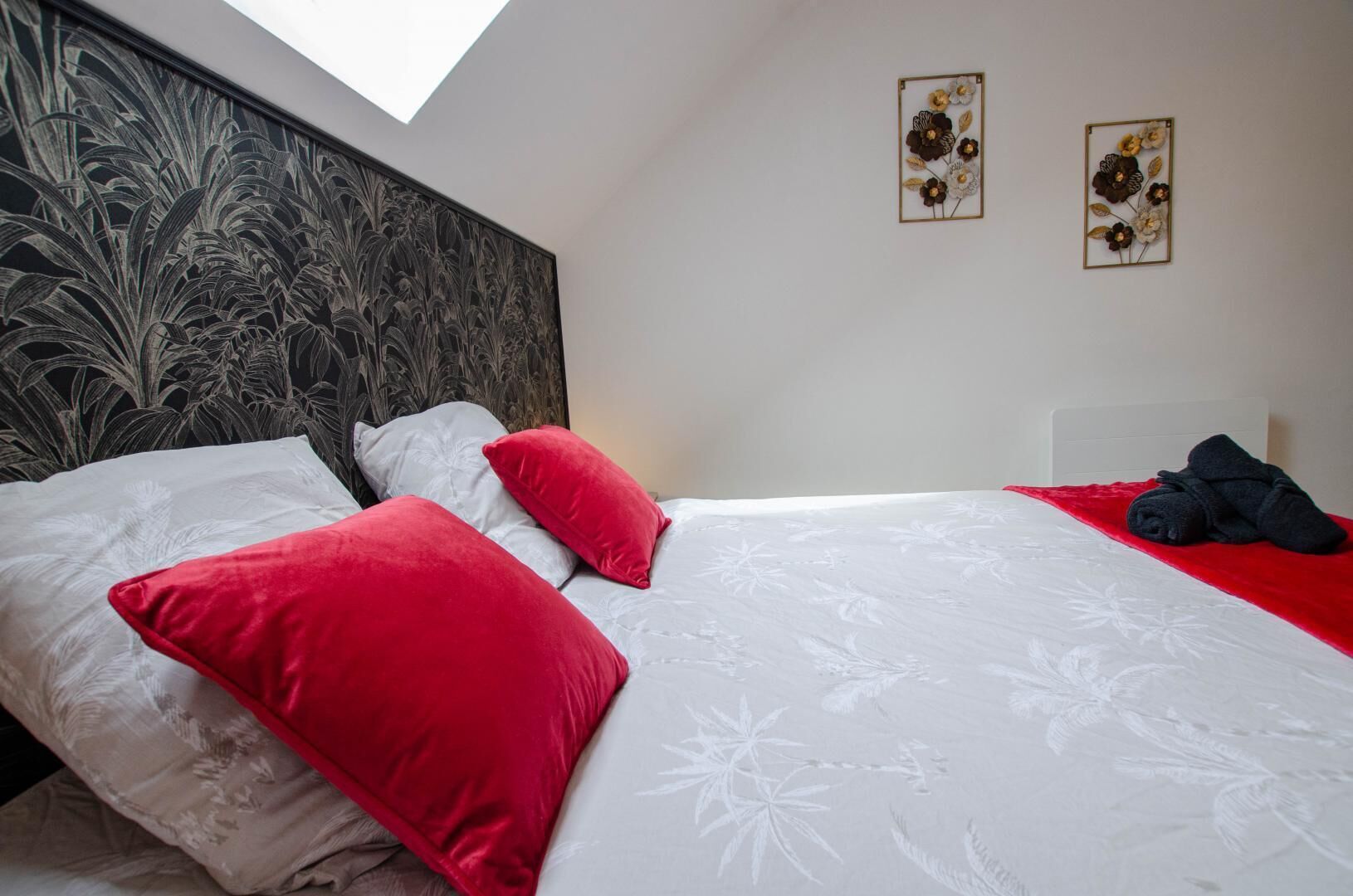 Une chambre à coucher avec un lit, des oreillers, une tête de lit et deux œuvres d’art murales.