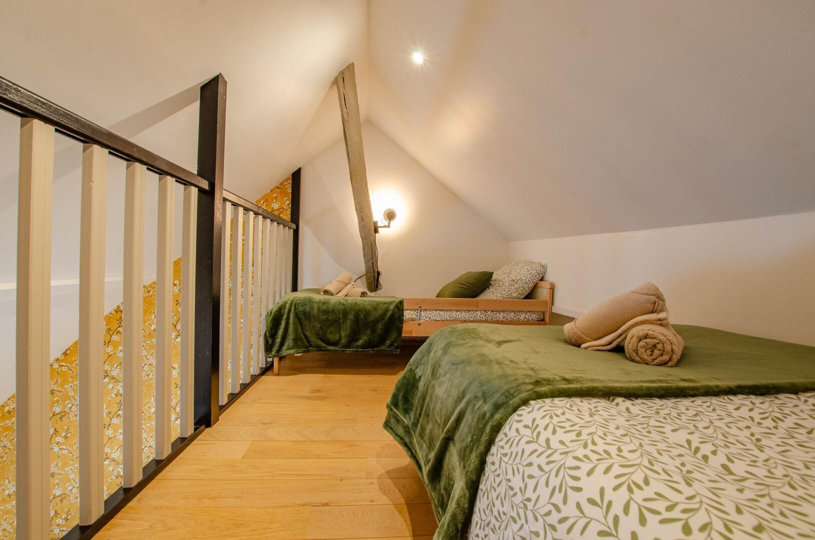 A bedroom with two beds, a wooden floor, and a sloped ceiling.