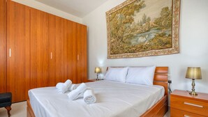 Ein Schlafzimmer mit einem großen Bett, einem Holzschrank, Nachttischen und einem Gemälde an der Wand.