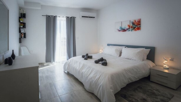 Ein modernes Schlafzimmer mit einem großen Bett, Nachttischen, einem Schreibtisch und einem Stuhl.