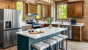 A modern kitchen with stainless steel appliances, wooden cabinets, and a central island with bar stools.