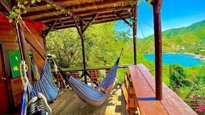 A hammock under a wooden pergola with a view of a lake and hills. - Tamarindo Beach Hostel  (Taganga)