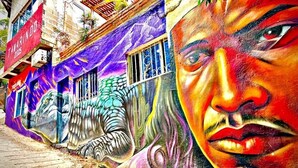 A building with vibrant graffiti art, including a large mural of a face and a winged creature. - Tamarindo Beach Hostel  (Taganga)