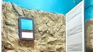 A bathroom with a stone wall, a sink, a toilet, and a shower. - Tamarindo Beach Hostel  (Taganga)