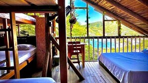 A wooden cabin with bunk beds and a balcony overlooking a scenic landscape. - Tamarindo Beach Hostel  (Taganga)