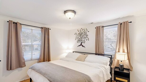 Ein Schlafzimmer mit Bett, Nachttisch, Lampe und einer an der Wand befestigten Baumdekoration.
