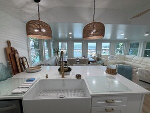 Eine moderne Küche mit einer großen Kochinsel, weißen Schränken und Blick auf das Wasser.