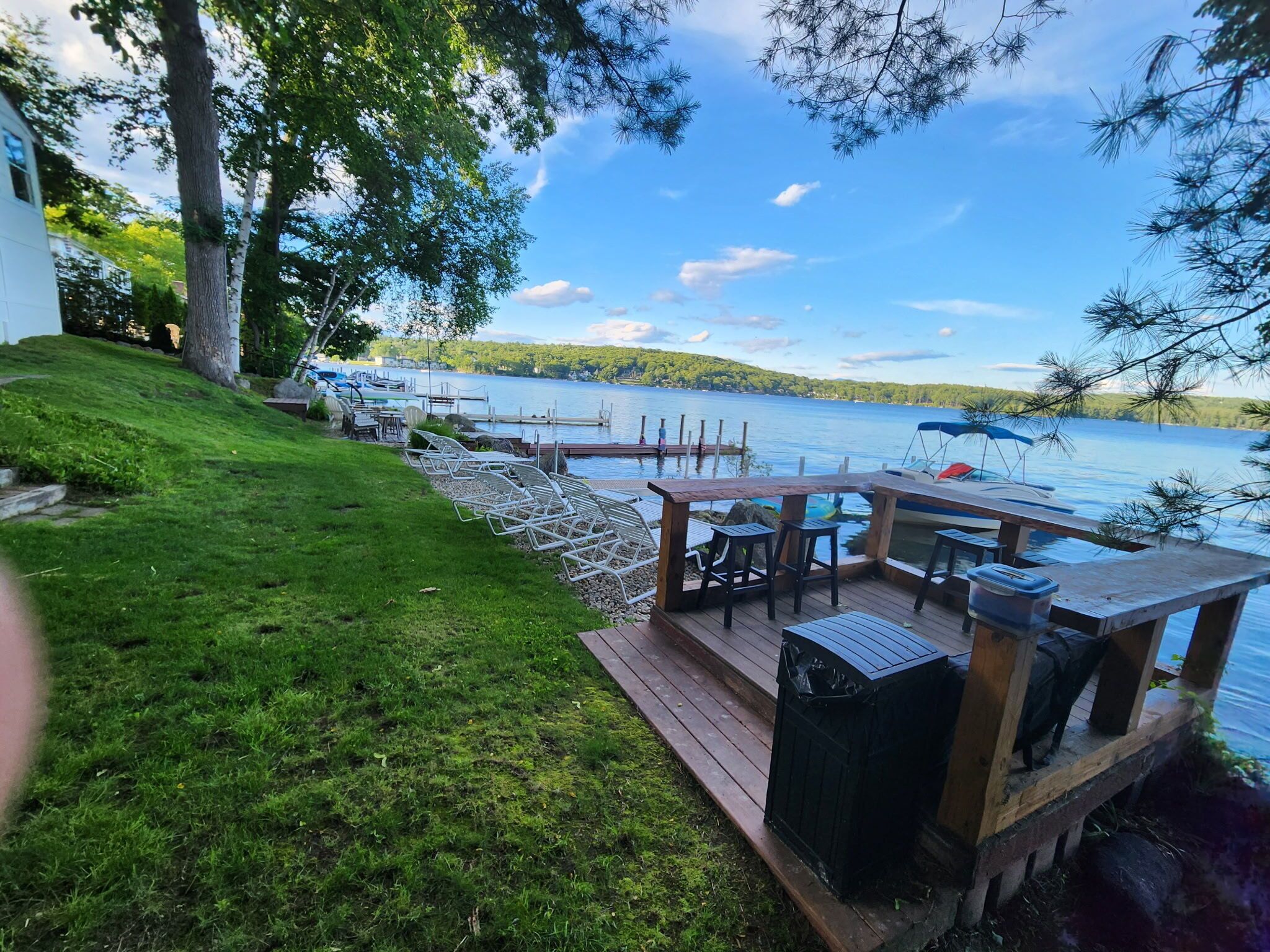 Una terraza a la orilla del lago con mobiliario exterior, un muelle y vistas al lago.