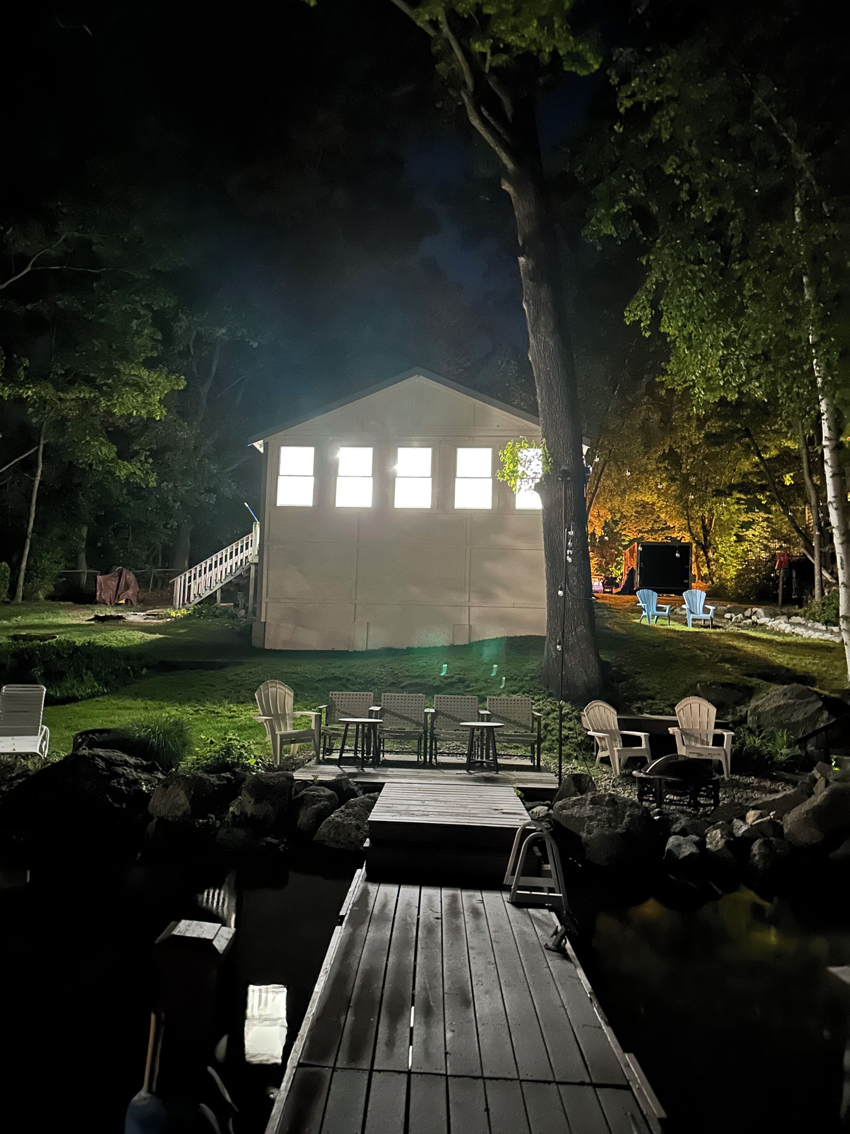 A building with a covered deck, outdoor seating, and a pond.
