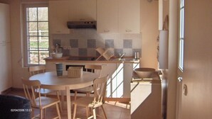 Eine Küche mit Holzausstattung, einem Esstisch mit Stühlen und einem Fenster, das natürliches Licht hereinlässt.
