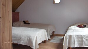 Ein Zimmer mit zwei Betten, einer Holzbalkendecke und einem kleinen Fenster.