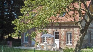 Ein Backsteinhaus mit einer kleinen Terrasse, einem Tisch und einem Stuhl.