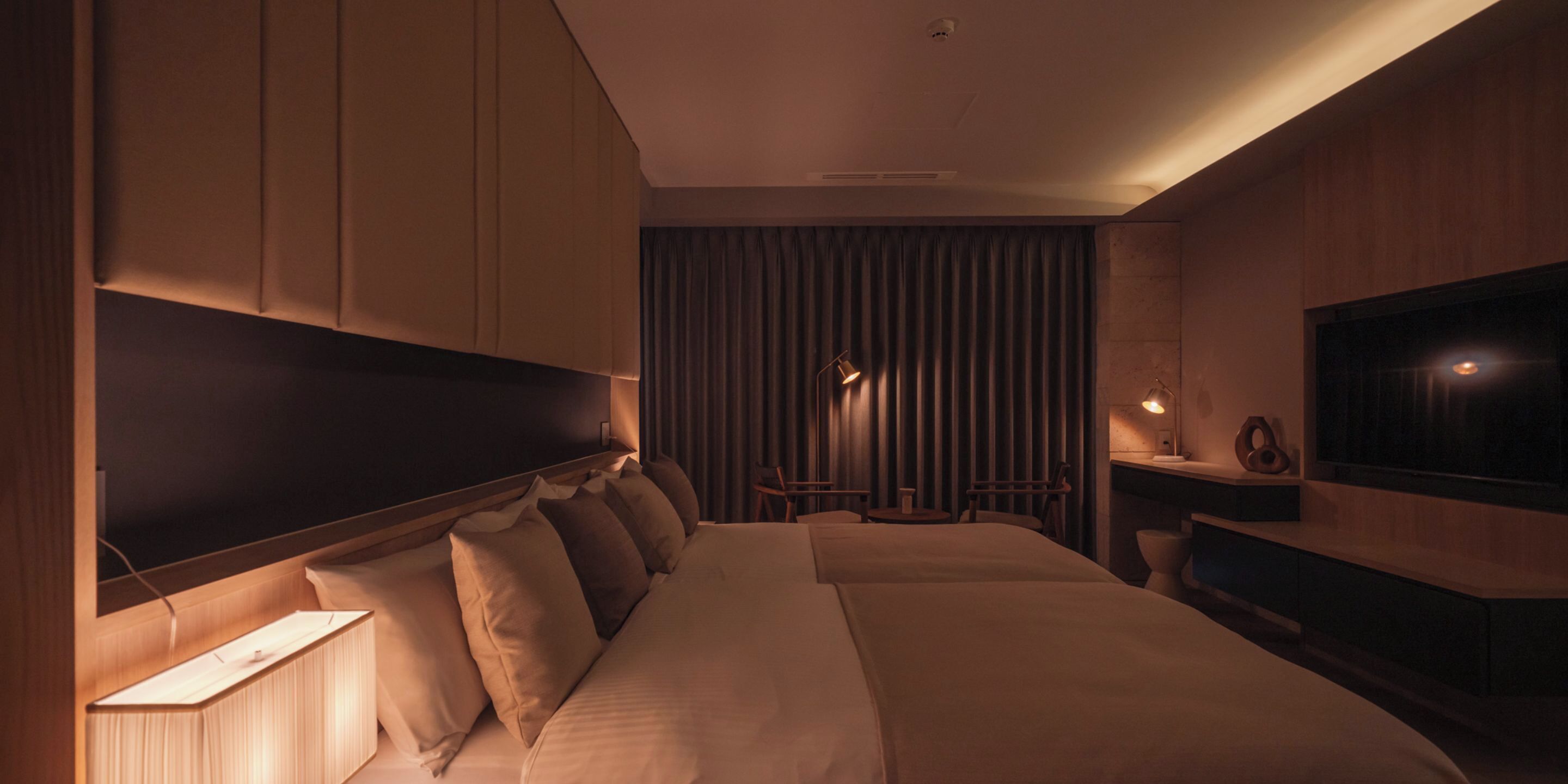 Una habitación de hotel moderna con una cama grande, un televisor y un escritorio con lámpara.