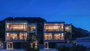 A modern two-story house with large glass windows and a flat roof. - CELEVI NANJO (Nanjo)